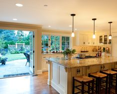 a large kitchen with an island and bar stools next to the sliding glass door