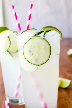 two glasses filled with cucumber and limeade on top of a wooden table