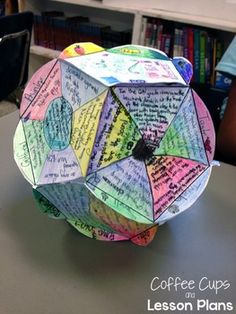 an origami umbrella made out of coffee cups on a table in front of bookshelves