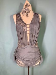 a mannequin wearing a gray dress with beading on the neck and shoulders