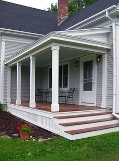 a porch with chairs and steps leading up to the front door on a gray house