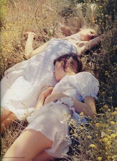 two women laying on the ground in tall grass