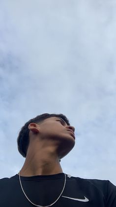 a man is looking up at the sky with his head tilted to the side, wearing a nike t - shirt