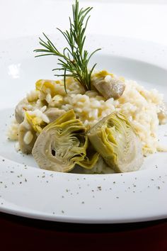 a white plate topped with rice and artichokes