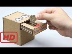 a hand is opening a cardboard box with a coin in it