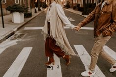 a man and woman crossing the street holding hands