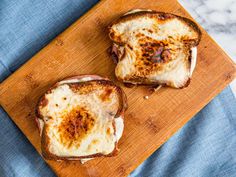 two toasted sandwiches sitting on top of a wooden cutting board