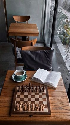 a wooden chess board sitting on top of a table next to a cup of coffee