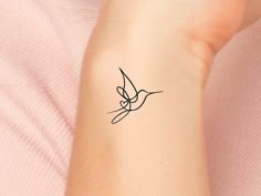 a woman's arm with a small tattoo design on the left side of her wrist