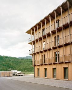 a large wooden building sitting on the side of a road next to a lush green hillside