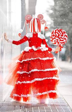 a woman in a red and white dress is holding a lollipop candy cane