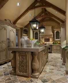 a large kitchen with an island in the center and two lamps hanging from the ceiling