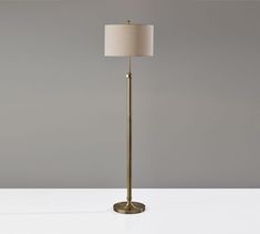 a gold floor lamp with a white shade on the top, and a beige linen shade on the bottom