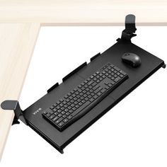 a computer desk with a keyboard and mouse attached to the back of it, sitting on top of a wooden table