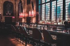 a long bar with lots of bottles and glasses on the top shelf in front of large windows