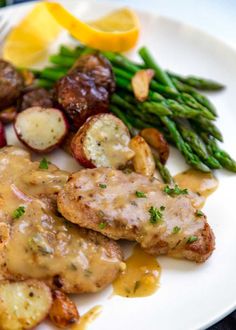 a white plate topped with meat, potatoes and asparagus