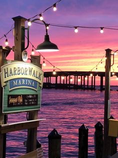 the harborwalk marina sign is lit up at sunset