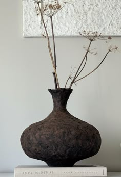 there is a vase with some flowers in it on top of a bookshelf