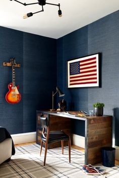 a bedroom with blue walls and an american flag hanging on the wall next to a desk