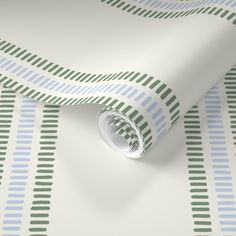 a white wallpaper with green and blue stripes on it's side, next to a roll of tape