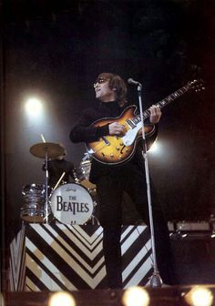 a man standing on top of a stage holding a guitar