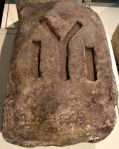 a stone with the word y on it is displayed in a museum display case next to other artifacts