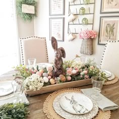 an easter table setting with flowers and bunny figurines in the centerpieces