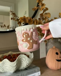 a person is holding a cup with two bears on it and some pumpkins in the background