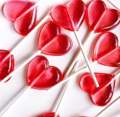 several heart shaped lollipops are on a white plate with toothpicks