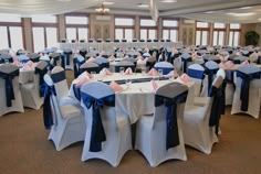 rows of banquet tables with blue and white sashes on them in a ballroom setting