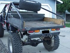 the truck is parked on the side of the road in front of a house with two large tires