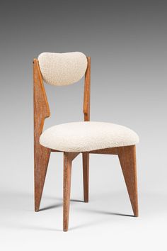 a wooden chair with a white upholstered seat and back rest on a gray background