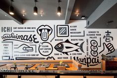 the interior of a restaurant with black and white graphics on the wall, along with wooden tables