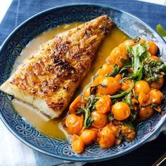 a blue plate topped with fish and vegetables