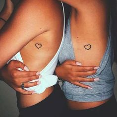 two women hugging each other with tattoos on their arms and chestes in the shape of hearts