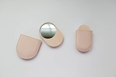 a pair of pink leather eyeglasses next to a mirror on a white surface