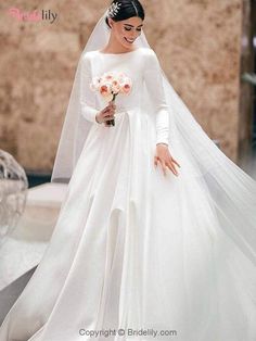 a woman in a white wedding gown and veil walking down the street with her hand on her hip