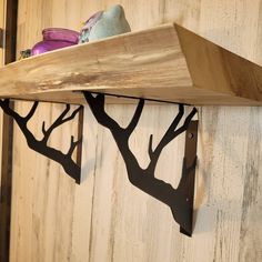 a wooden shelf with two metal hooks on it