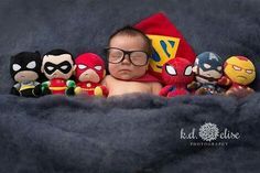 a baby is surrounded by stuffed toys and dressed as the avengers, including captain america