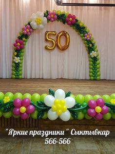 the balloon arch is decorated with flowers, leaves and balloons for an 50th birthday party