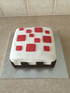 a cake with white and red icing on top of a counter next to a tile wall