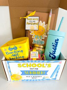 an open box with school supplies inside on a white tableclothed surface, in front of a cardboard box that says school's out for summer