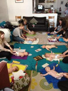 a group of people sitting around each other on the floor with babies in diapers