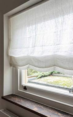 a window with a white curtain hanging from it's side