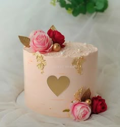 there is a pink cake with gold decorations on the top and roses on the bottom