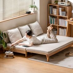 a woman laying on top of a bed next to a book shelf filled with books