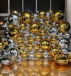 a bunch of shiny balls sitting on top of a wooden table next to a window