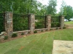 a stone and iron fence in the middle of a yard