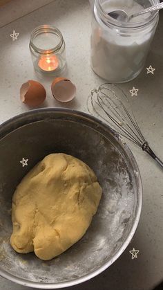 dough in a metal bowl next to an egg and whisk on a counter