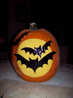 a pumpkin with bats painted on it in the shape of a bat, sitting on a tile floor